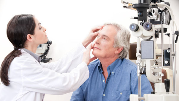 Eye doctor giving elderly man an eye check-up at Big City Optical.
