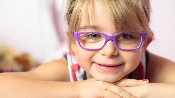 Little girl wearing purple eyeglasses.
