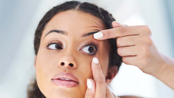 Woman checking the fit of contact lens on her eye.