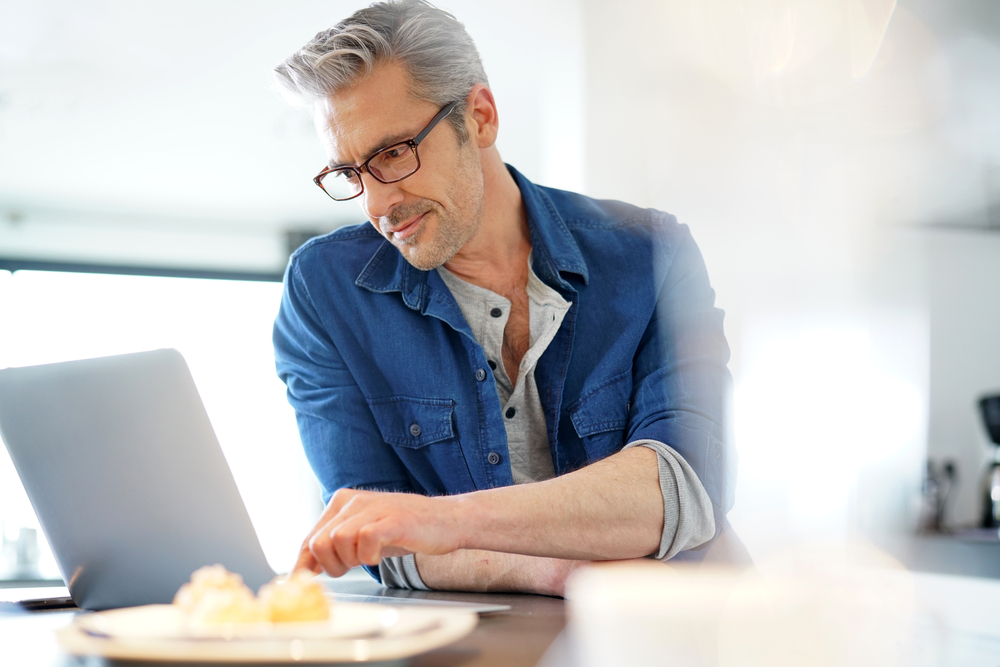 Man wearing eyeglasses while browsing his computer.