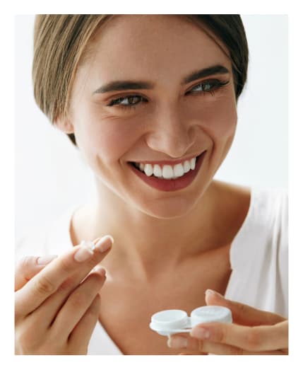 Smiling woman holding a contact lens case<br />
