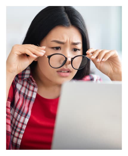 Woman holding her glasses in front of her laptop
