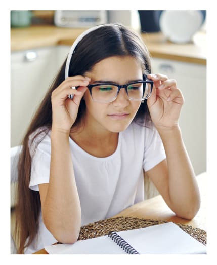 Girl wearing eyeglasses experiencing difficulty while reading<br />
