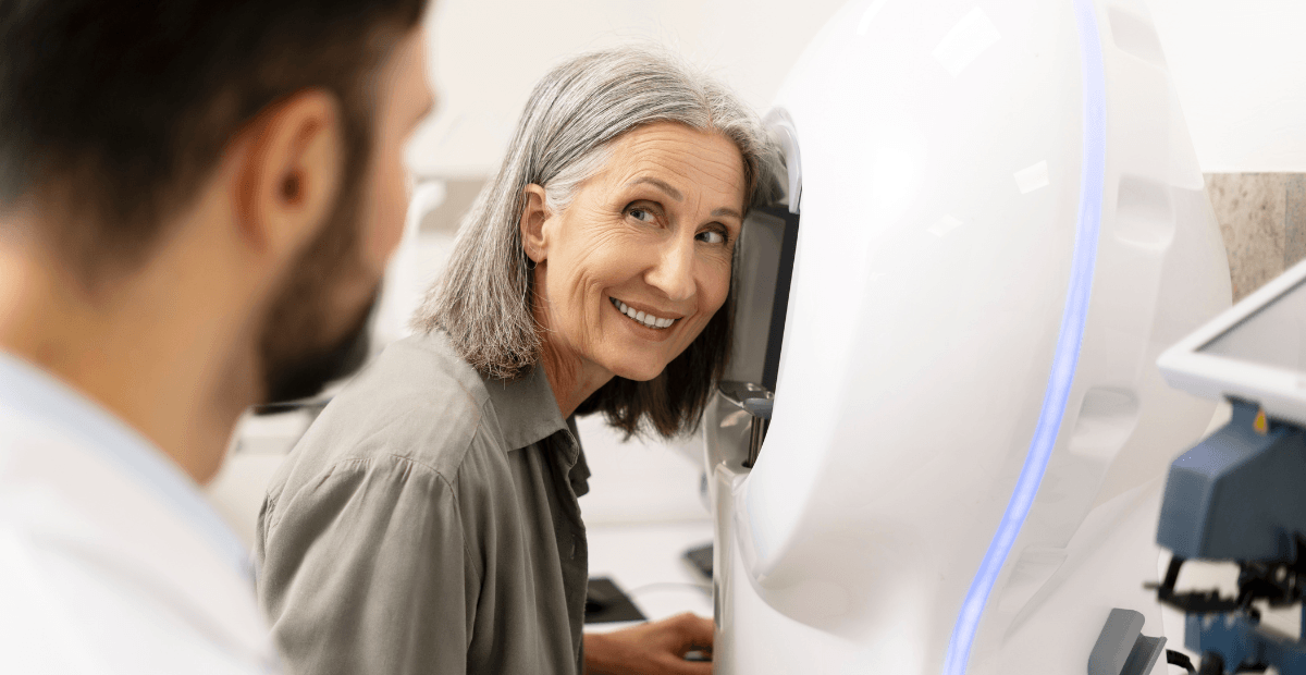 Smiling older woman getting an eye exam with advanced equipment.